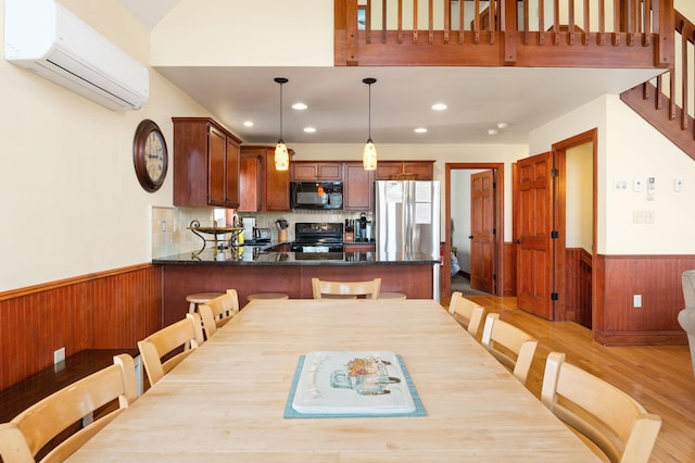 dining space featuring a wall mounted air conditioner, light wood-type flooring, recessed lighting, wooden walls, and wainscoting