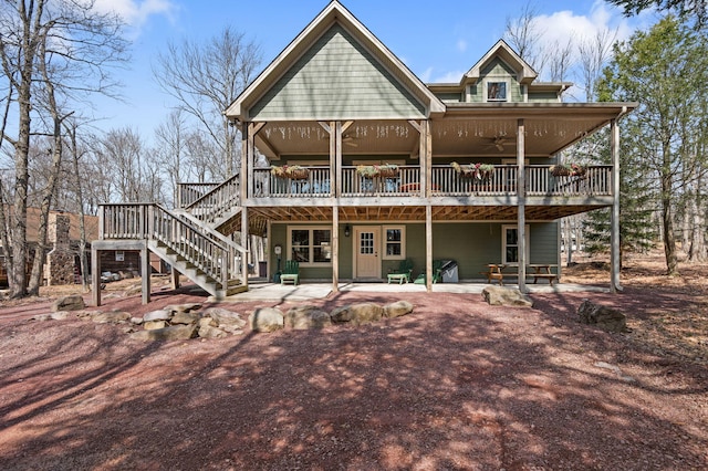 back of house featuring stairway, a wooden deck, a ceiling fan, and a patio area