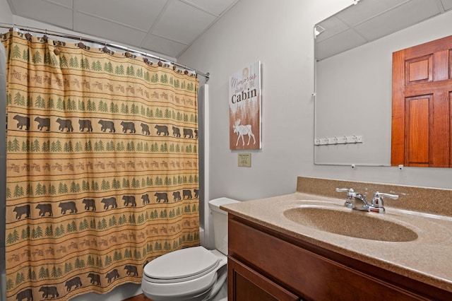 bathroom with vanity, toilet, a paneled ceiling, and shower / bathtub combination with curtain