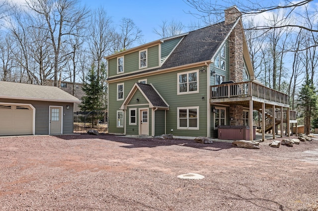 view of front of house featuring a hot tub, stairway, a wooden deck, roof with shingles, and driveway