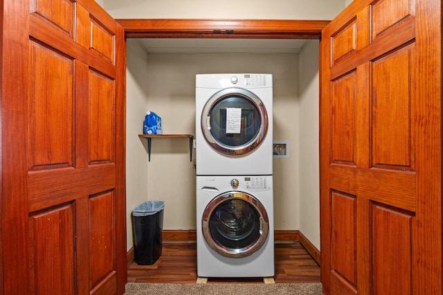 washroom featuring laundry area, stacked washer / drying machine, baseboards, and wood finished floors