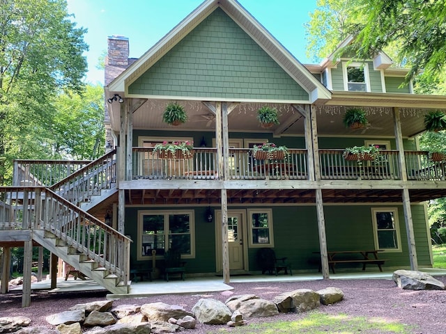 rear view of house with stairway, a patio area, and a chimney