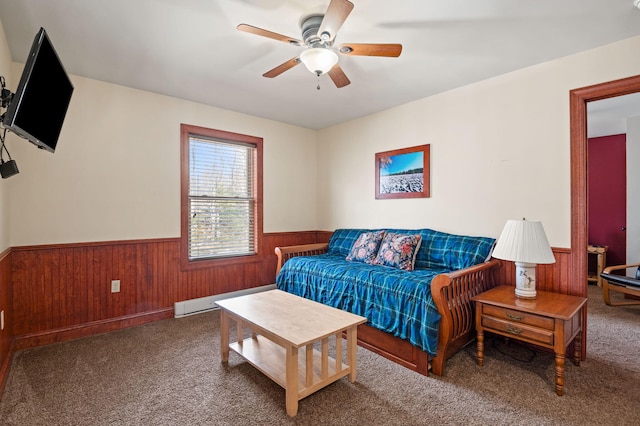 living room with a baseboard heating unit, carpet flooring, a wainscoted wall, and ceiling fan