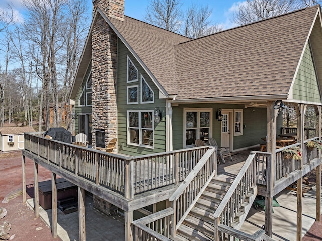 view of front of home with a wooden deck, stairway, a chimney, and a shingled roof