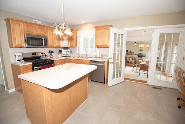 kitchen with visible vents, stainless steel appliances, hanging light fixtures, light countertops, and a center island