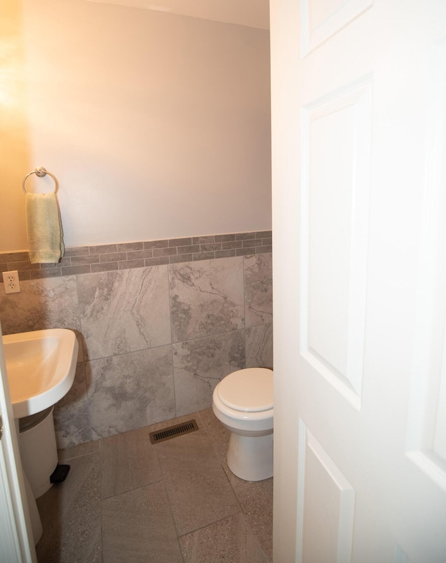 bathroom with visible vents, a wainscoted wall, toilet, tile walls, and tile patterned flooring