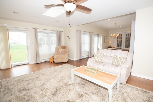 living area with a wealth of natural light, wood finished floors, and ceiling fan with notable chandelier