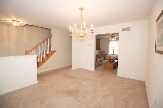 carpeted empty room with visible vents, baseboards, ceiling fan with notable chandelier, and stairway