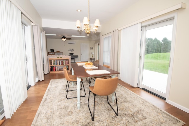 dining space featuring ceiling fan with notable chandelier, a wall unit AC, recessed lighting, and light wood-style floors