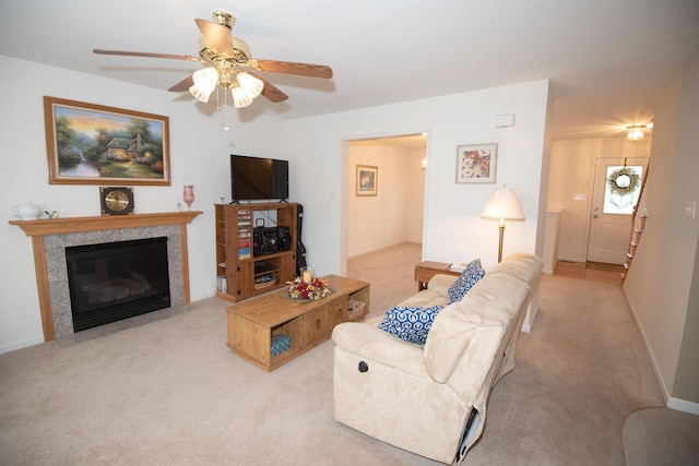 living area with carpet flooring, a tile fireplace, baseboards, and ceiling fan