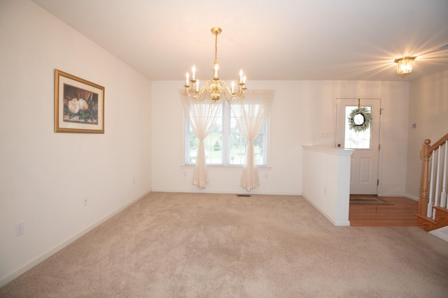 unfurnished room featuring an inviting chandelier, a wealth of natural light, and carpet floors