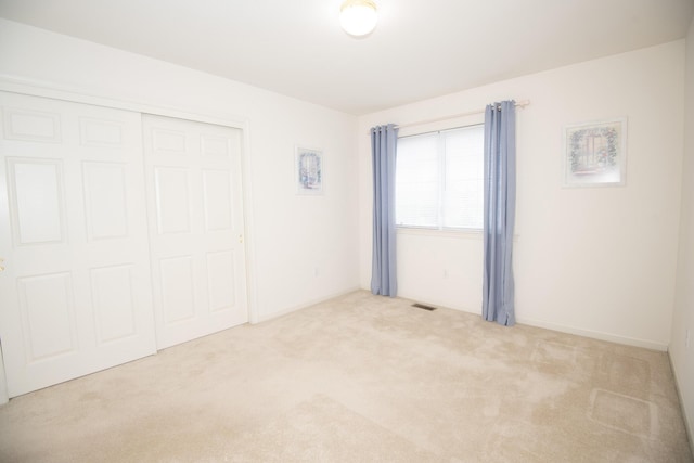 unfurnished bedroom featuring a closet, carpet floors, and visible vents