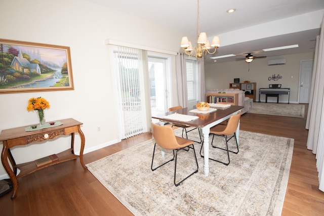 dining space with recessed lighting, ceiling fan with notable chandelier, a wall unit AC, and wood finished floors