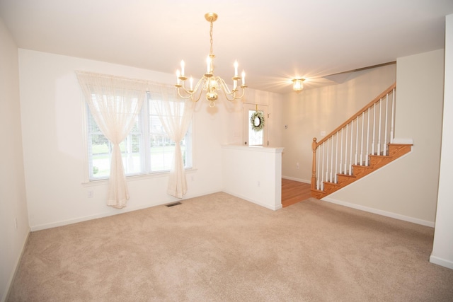 carpeted spare room featuring stairway, baseboards, visible vents, and a chandelier