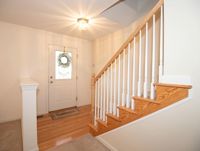 foyer entrance featuring stairs, wood finished floors, visible vents, and baseboards