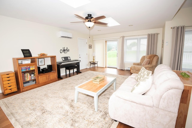 living area featuring a wall mounted AC, wood finished floors, a skylight, baseboard heating, and ceiling fan