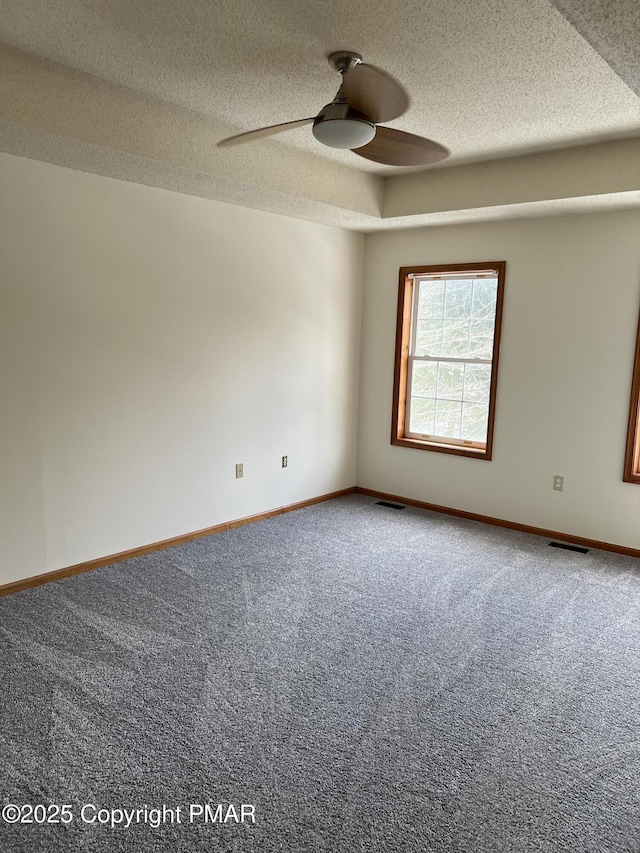 empty room with ceiling fan, a textured ceiling, and carpet