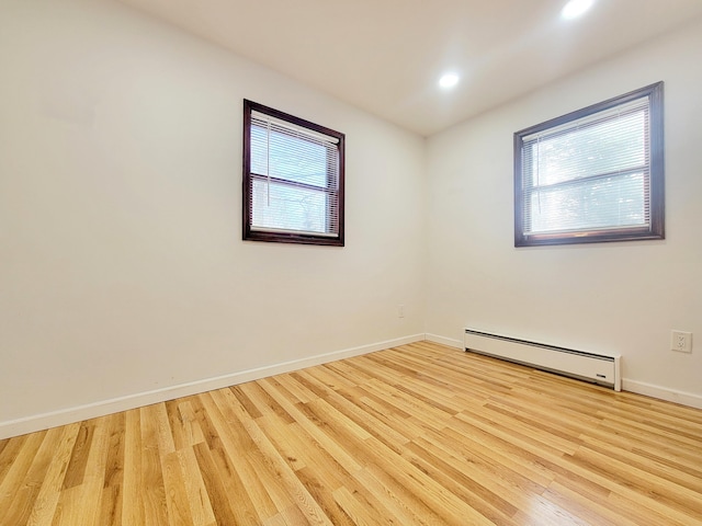 empty room with light wood-style flooring, a baseboard heating unit, baseboards, and recessed lighting