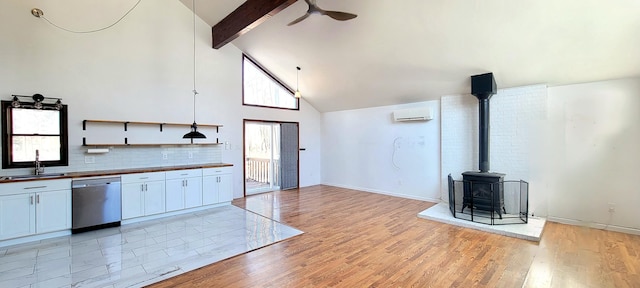 kitchen featuring beamed ceiling, light wood-style flooring, a wood stove, a sink, and dishwasher