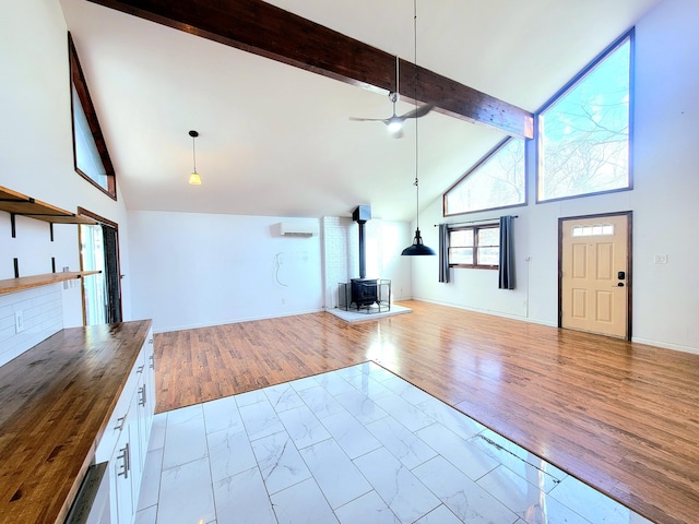 unfurnished living room featuring baseboards, a wood stove, marble finish floor, high vaulted ceiling, and beam ceiling