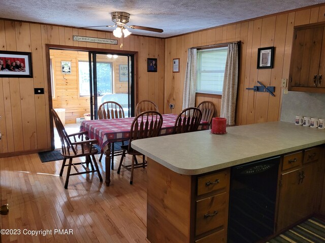21 Cherry Ct, Clifton Township, PA 18424 - dining space featuring a textured ceiling, ceiling fan, wood walls, light wood-type flooring, and wine cooler