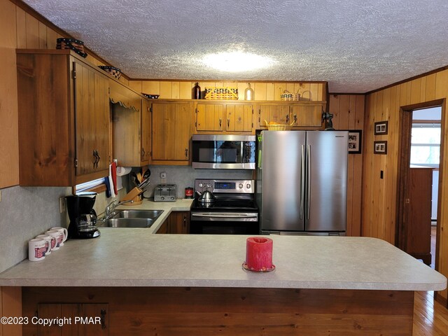 21 Cherry Ct, Clifton Township, PA 18424 - kitchen with appliances with stainless steel finishes, light countertops, a textured ceiling, a peninsula, and brown cabinetry