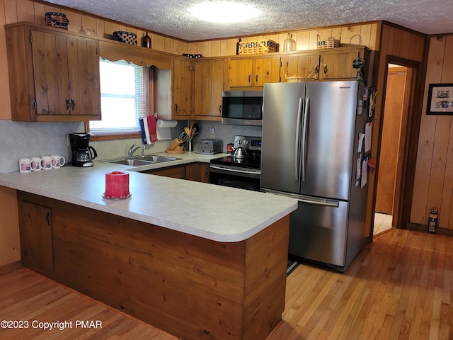 21 Cherry Ct, Clifton Township, PA 18424 - kitchen with stainless steel appliances, a sink, a peninsula, light countertops, and brown cabinetry