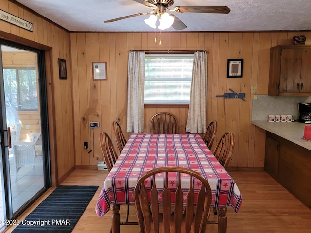 21 Cherry Ct, Clifton Township, PA 18424 - dining room featuring light wood-style floors, a textured ceiling, wood walls, a ceiling fan, and crown molding