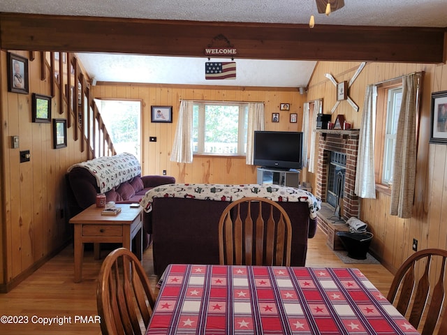 21 Cherry Ct, Clifton Township, PA 18424 - dining space featuring beamed ceiling, wooden walls, light wood-type flooring, a brick fireplace, and baseboards