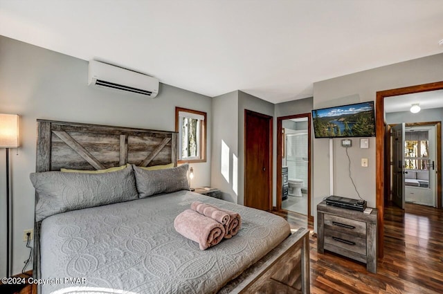 bedroom with ensuite bath, an AC wall unit, and wood finished floors