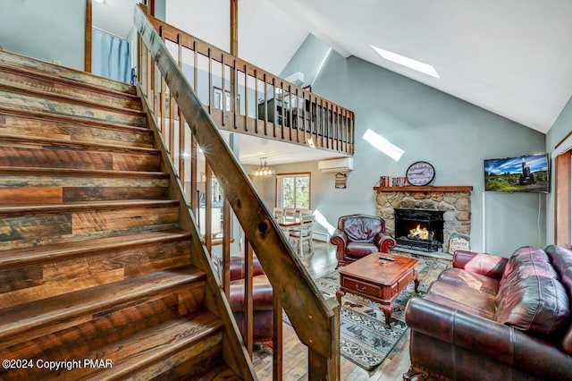 living room featuring a skylight, stairway, wood finished floors, a wall mounted air conditioner, and a fireplace