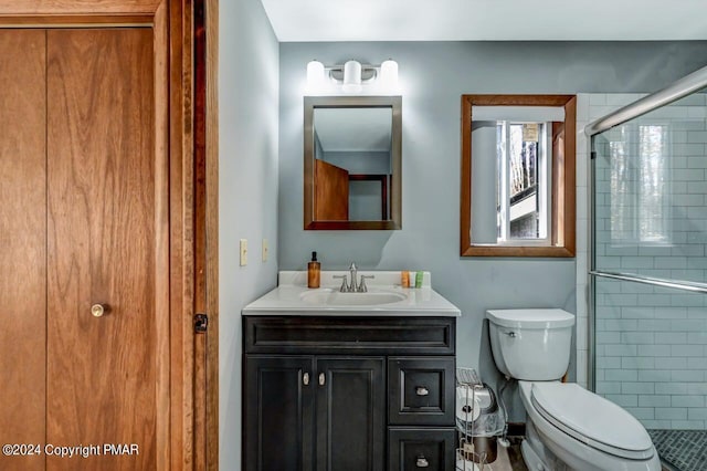 bathroom with toilet, a shower stall, and vanity