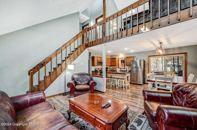 living area with stairway, light wood-style flooring, and a high ceiling