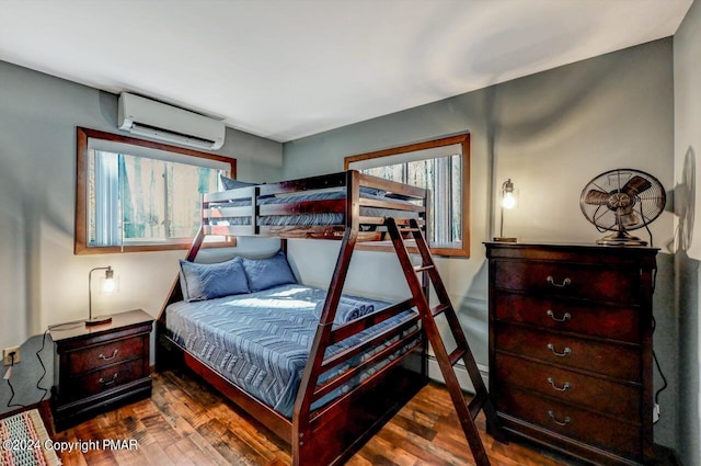 bedroom with a wall unit AC, a baseboard heating unit, and wood finished floors