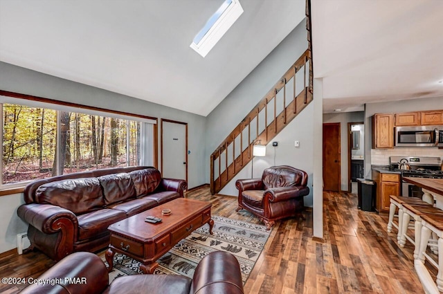 living area featuring lofted ceiling with skylight, stairway, and wood finished floors