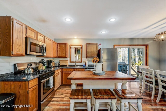 kitchen featuring stainless steel appliances, light wood finished floors, a sink, and tasteful backsplash