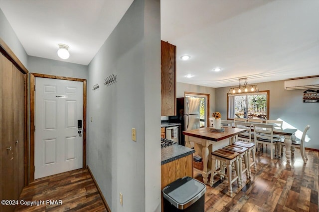 kitchen featuring dark countertops, a wall mounted air conditioner, dark wood finished floors, and freestanding refrigerator