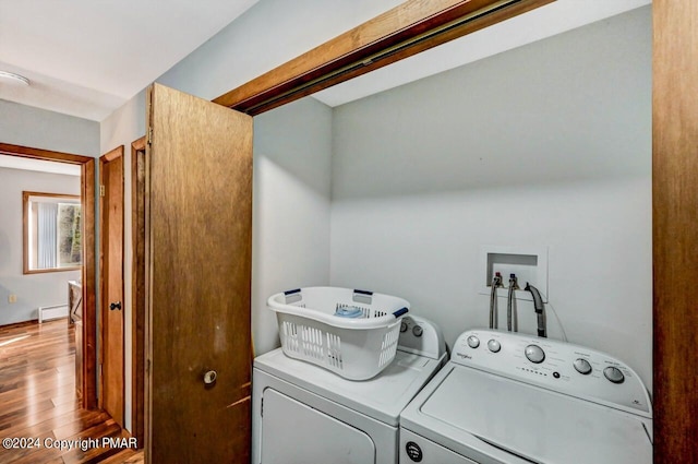 washroom with laundry area, a baseboard radiator, washer and dryer, and wood finished floors