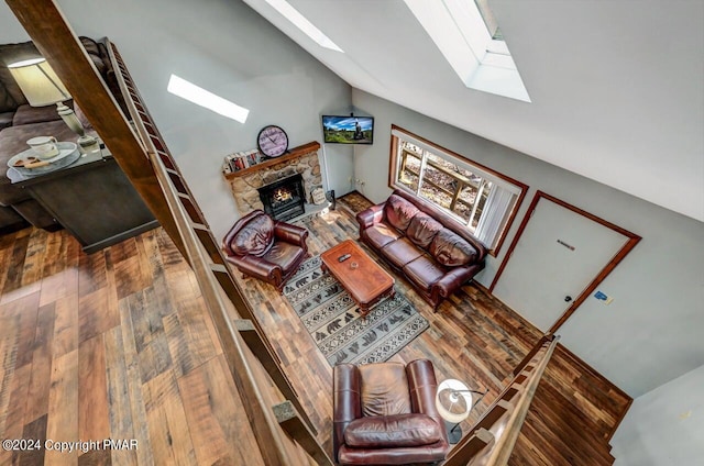 living room featuring vaulted ceiling with skylight, a fireplace, and hardwood / wood-style floors