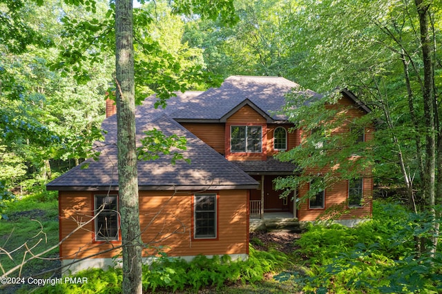 rustic home featuring roof with shingles and a chimney