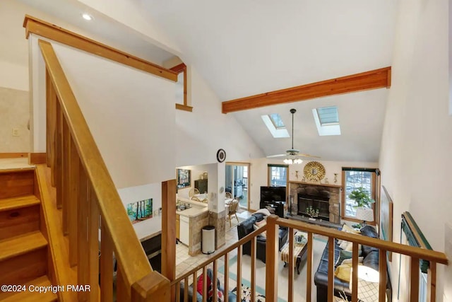 482 Spruce Dr, Tannersville, PA 18372 - staircase with high vaulted ceiling, a skylight, ceiling fan, a glass covered fireplace, and beamed ceiling