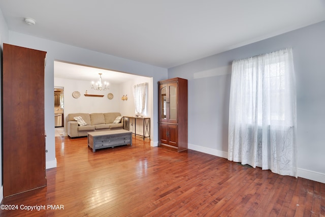 living room with dark wood-type flooring, a notable chandelier, and baseboards