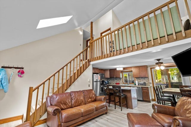 206 Maxatawny Dr, Pocono Lake, PA 18347 - living room with a skylight, stairs, light wood-style floors, high vaulted ceiling, and a ceiling fan