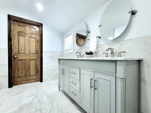143 Cathleen Dr, East Stroudsburg, PA 18302 - bathroom with tile walls, double vanity, marble finish flooring, vaulted ceiling, and a wainscoted wall