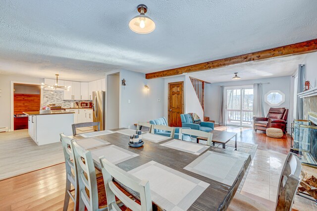 143 Cathleen Dr, East Stroudsburg, PA 18302 - dining room featuring a textured ceiling, a chandelier, light wood-type flooring, stairway, and beam ceiling