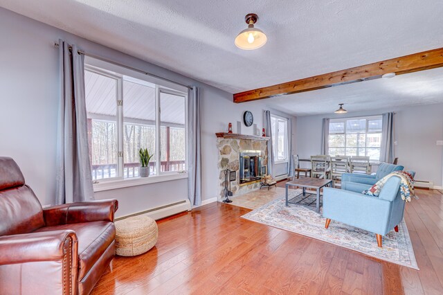 143 Cathleen Dr, East Stroudsburg, PA 18302 - living area with baseboard heating, beam ceiling, wood finished floors, a stone fireplace, and a baseboard radiator