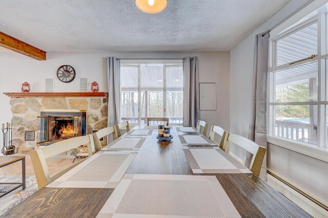 143 Cathleen Dr, East Stroudsburg, PA 18302 - dining area featuring a baseboard radiator, a textured ceiling, plenty of natural light, a stone fireplace, and beam ceiling
