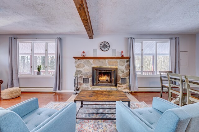 143 Cathleen Dr, East Stroudsburg, PA 18302 - living area featuring wood finished floors, a textured ceiling, plenty of natural light, baseboard heating, and a stone fireplace