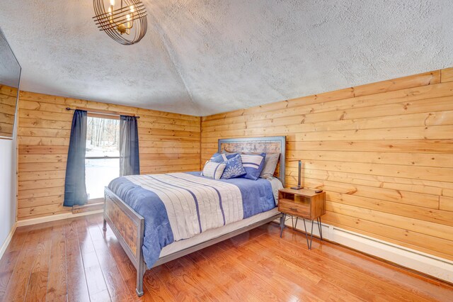 143 Cathleen Dr, East Stroudsburg, PA 18302 - bedroom featuring a textured ceiling, hardwood / wood-style floors, baseboard heating, baseboards, and wood walls