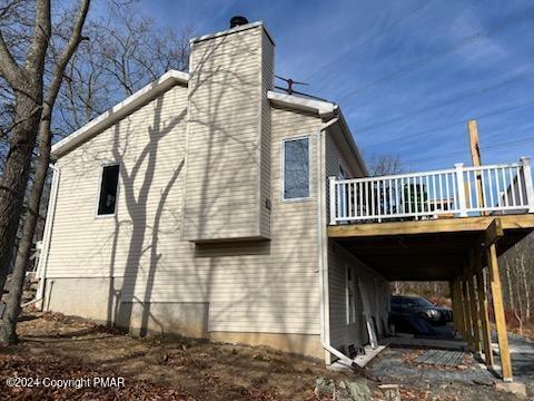 view of home's exterior featuring a wooden deck and a chimney